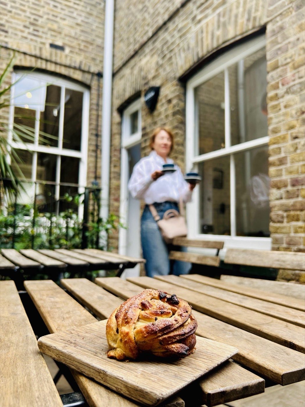 A cardamom bun served on a wooden board in the HJEM courtyard