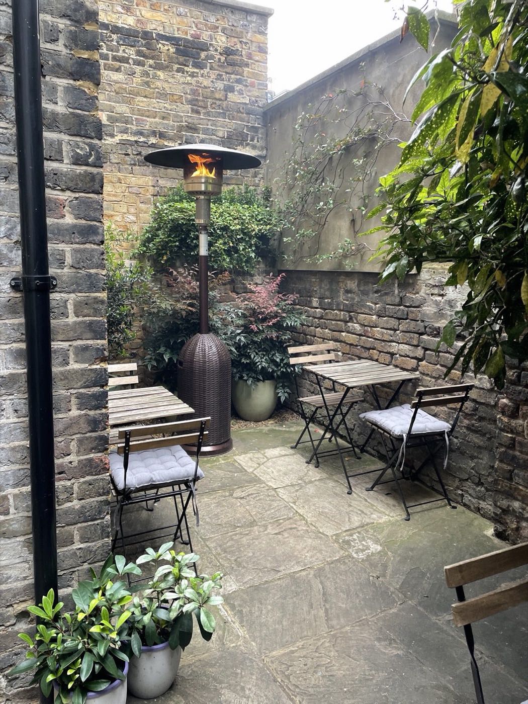 The small walled garden behind HJEM — brick walls, bistro tables and a patio heater